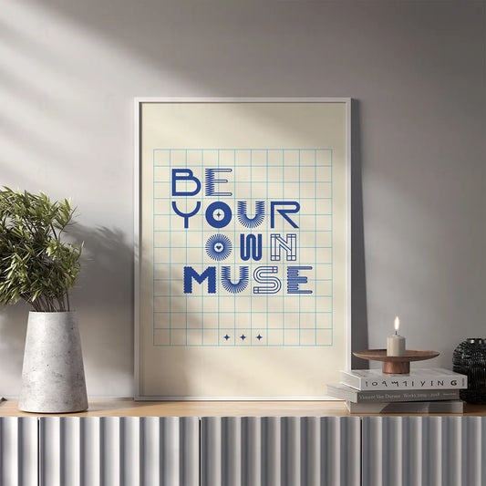 Plakat "Be Your Own Muse" wiszący w salonie
